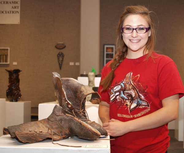 Female Honors student standing with a pair of ceramic boots.