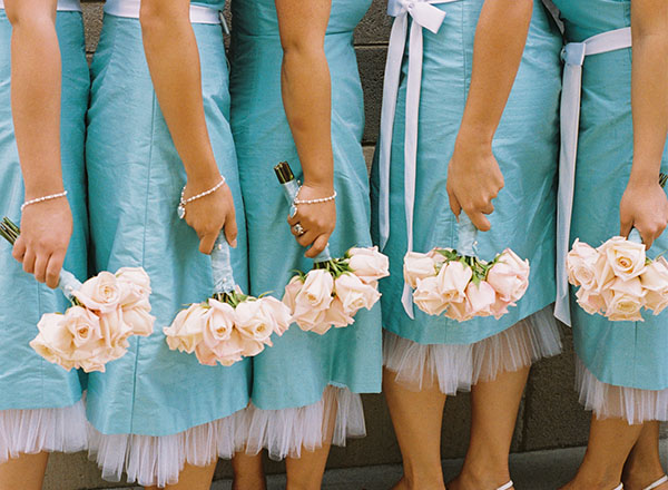 Five bridesmaids wearing the same blue dress and holding bouquets. 