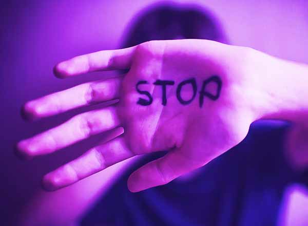 Hand with the word STOP held up in front of a person.