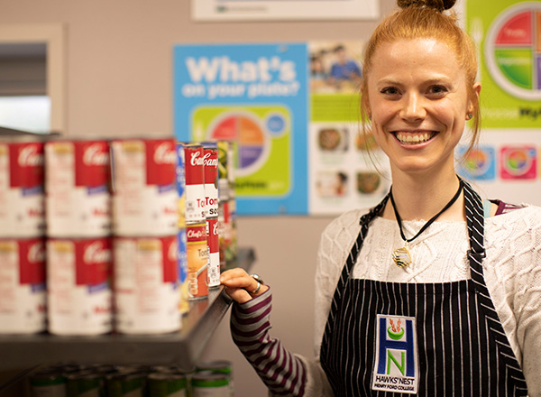 An image of a Hawks' Nest volunteer with canned goods. 