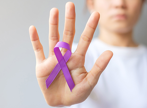 Woman in background, palm in foreground with purple ribbon
