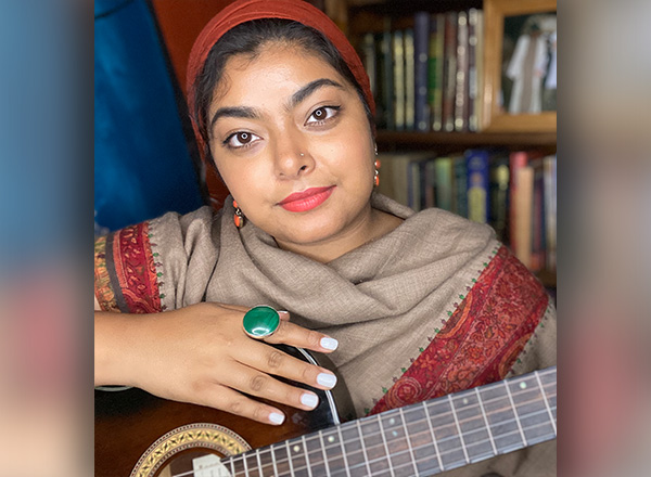 A photo of Tazeen Ayub holding a guitar.