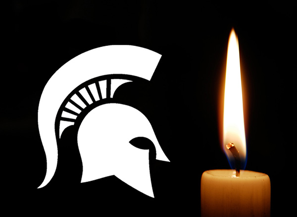 MSU Spartan helmet next to a lit vigil candle.