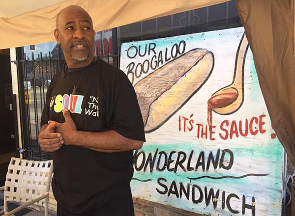 Chef Greg Beard in front of a sign for the Boogaloo Wonderland sandwich.