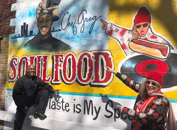 From L-R: Chef Greg Beard and Emmy-winning singer/songrwriter Allee Willis in front of a Soul Food wall mural.