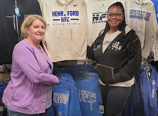 Two College Store employees showing off Henry Ford College merchandise. 