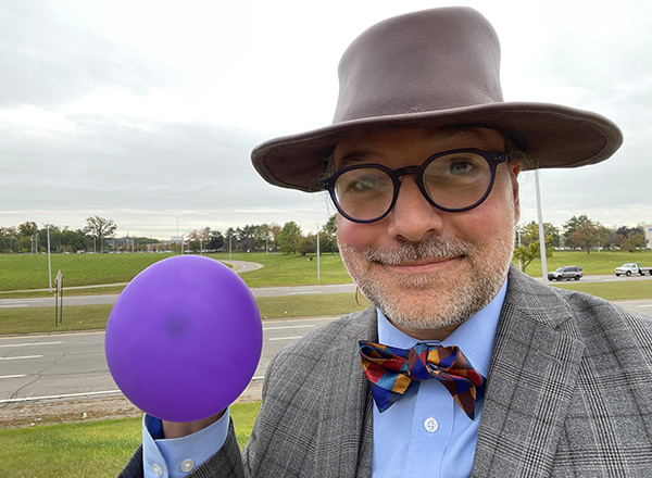 Jesse Mason holds up a purple balloon that stands in for Jupiter across from Ford Road. 