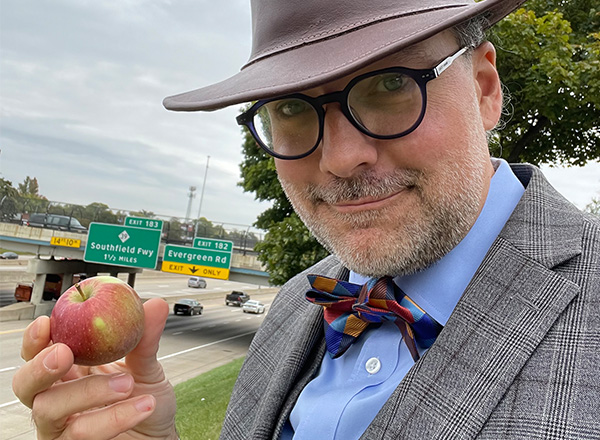 Jesse Mason holds up an apple, which is supposed to be Neptune, near I-96. 
