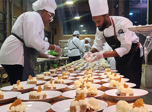 Culinary instructor and student prepare a table of desserts. 