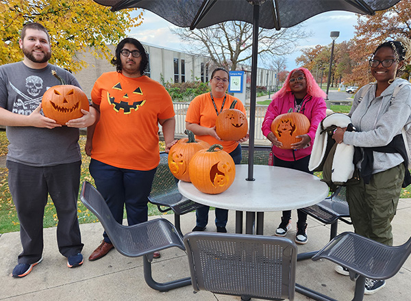 From L-R: Todd Hakim, HFC student Ahmed Altaee, Kelly Baratono, HFC student Lauren Whitley, and HFC student Lindizga Mkangama show off their pumpkins before lighting them. 