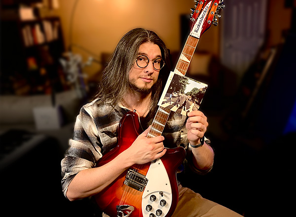 Anthony Lai with his guitar and a photo of the Beatles.