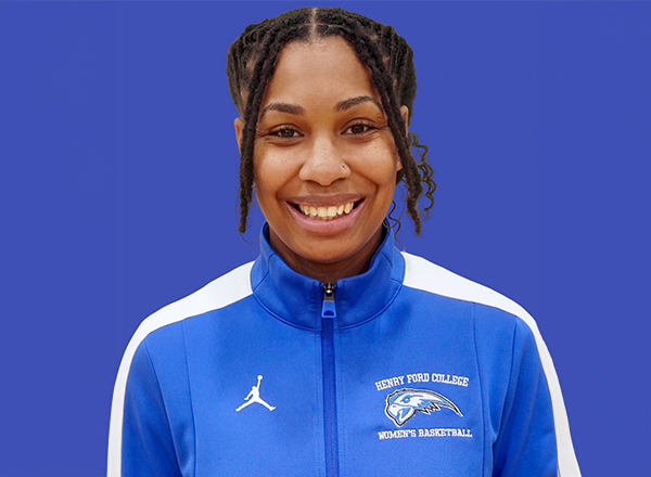 Shaunie Hankins smiling and wearing a blue and white Henry Ford College Women's Basketball jacket.