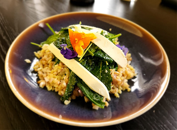 A plate of healthy food with greens and grains.