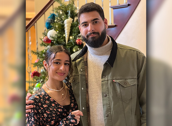 Lea Zaytoun, with her brother Ali Zaytoun, with a holiday tree in the background. 