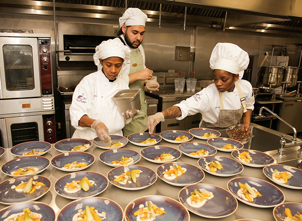Three HFC Culinary students preparing dishes for the Fall Scholarship dinner in fall of 2023.