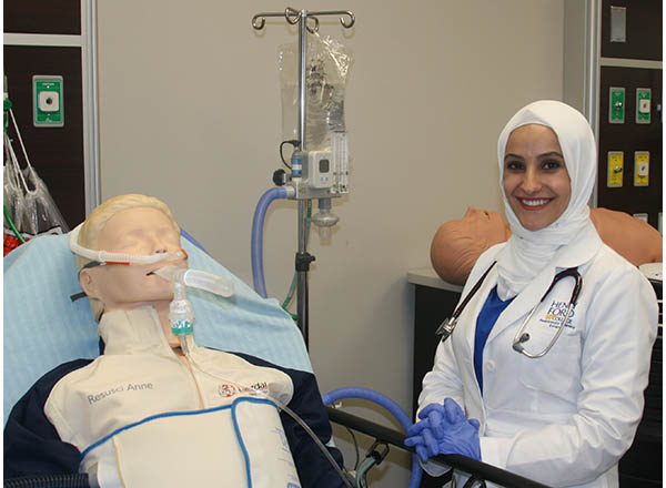 Photo of a respiratory therapist student with a training mannequin in a simulated hospital setting. 