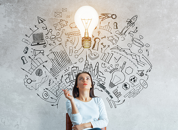 woman in chair in front of drawing of tech concepts, lightbulb at top