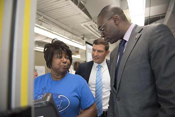 A student demonstrates robotic technology for President Kavalhuna and Lt. Gov. Gilchrist