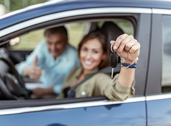 Woman leaning out car window holding keys