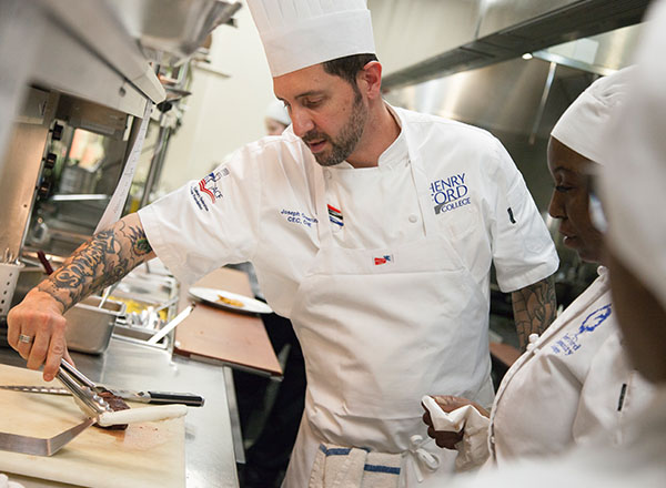 Chef Cosenza preparing a meal as culinary students watch.
