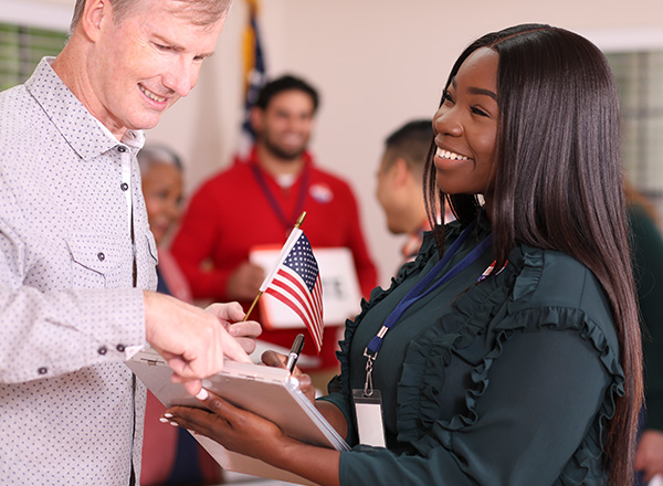 Volunteer works at polling place in the USA election assisting voter with his registration.