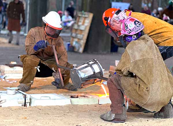Members of the Ironic Femmes pour the hot metal into molds.