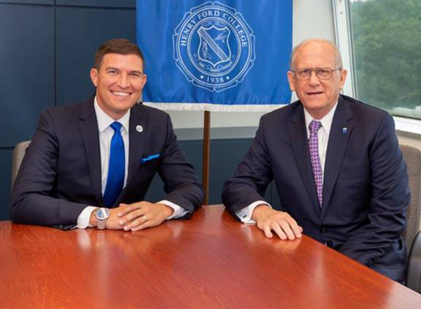 President Russ Kavalhuna and John McDonald sitting at a desk smiling at the camera.