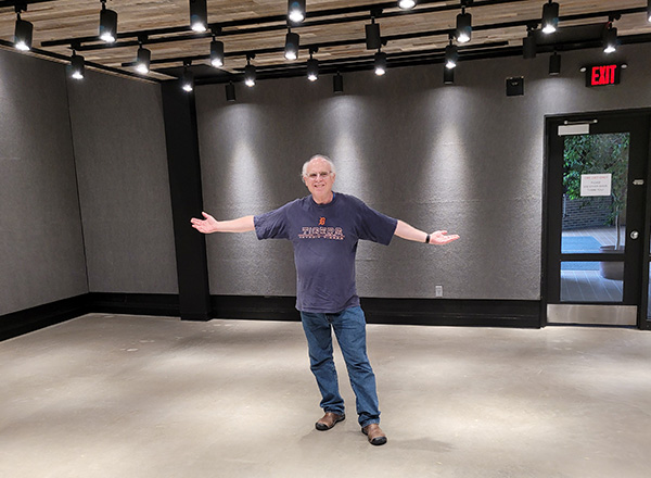 Steve Glazer standing in the middle of the gallery with his arms outstretched.