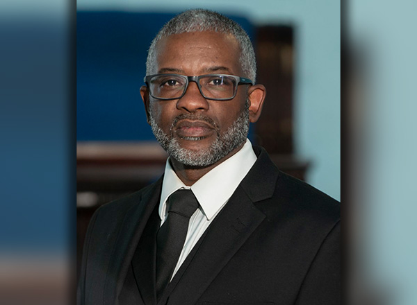 Darryl Stanbrough wearing a suit and glasses.