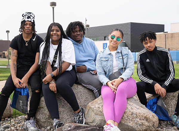 Students gather together, sitting on rocks.