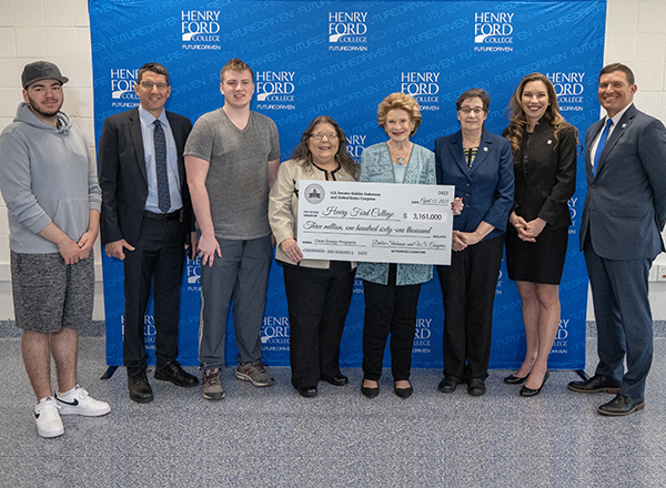 Group of people standing in front of backdrop, displaying an oversize check.
