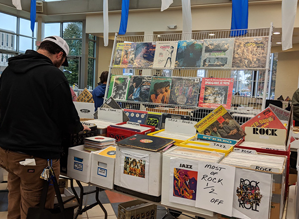 A patron of the WHFR Record Show perusing through one of the record show's collection of vinyl.