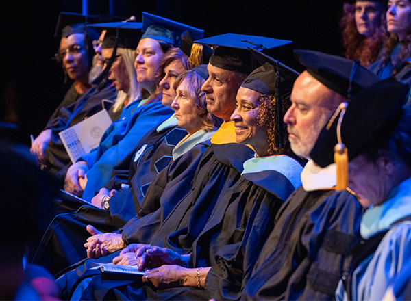 HFC faculty dressed in their regalia on stage