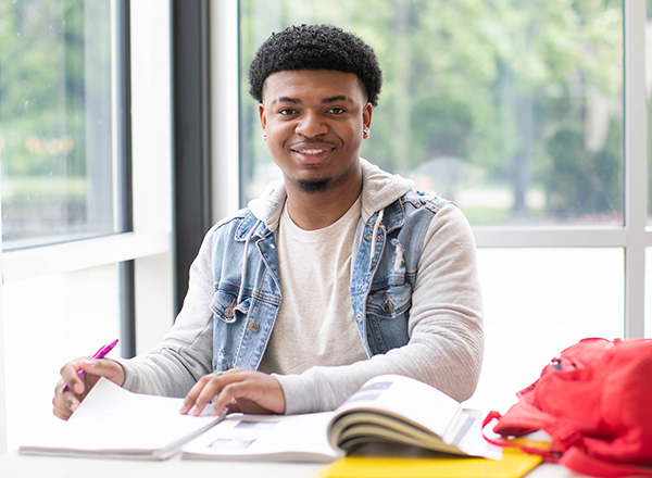 Student smiling and working on paperwork.