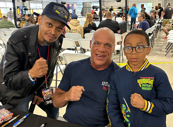 Houston and his dad with wrestling star Kurt Angle holding up fists. 