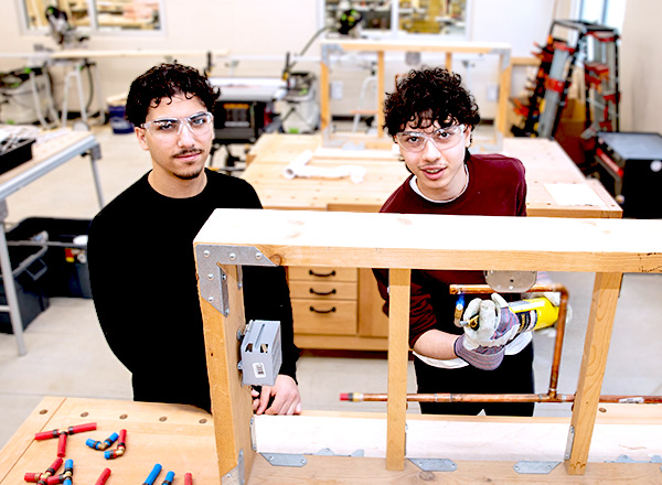 Two students working with construction tools.