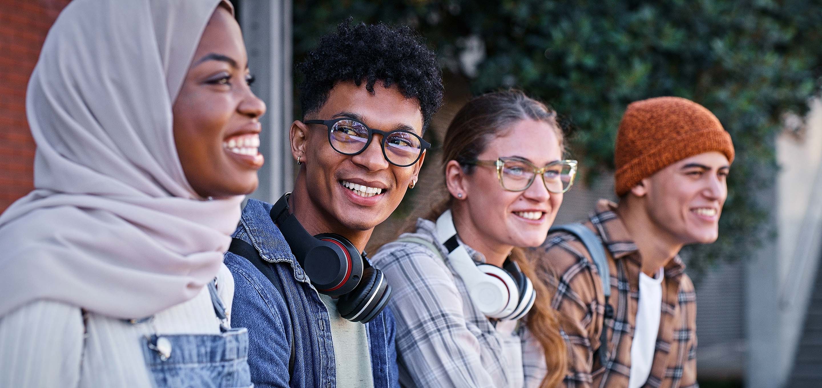 Closeup of four smiling college students sitting outside