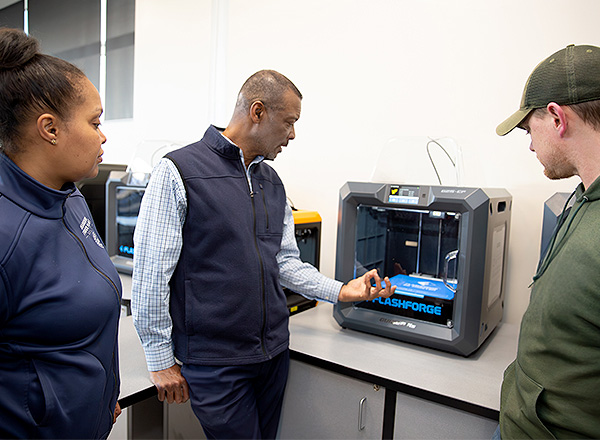 Instructor showing students the 3d printer.