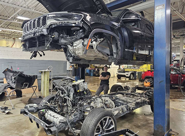 Georgia Travis standing between a car that has been taken apart.
