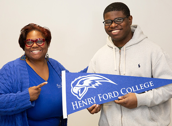 An HFC employee and student holding an HFC pennant. 