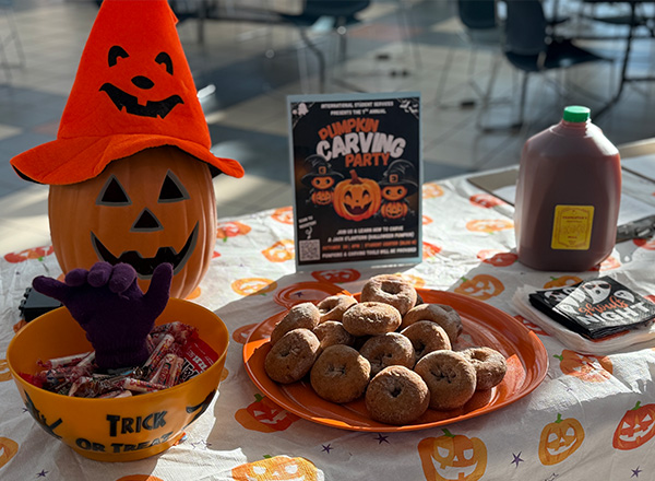 Table set up with Halloween goodies like donuts, cider, and candy.