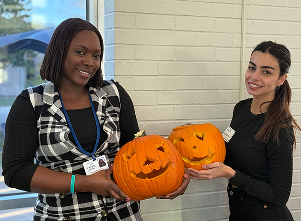 Two students holding their completed carved pumpkins. 