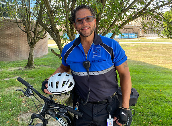 Rafael Rivera, Jr. posing with his patrol bike on campus.