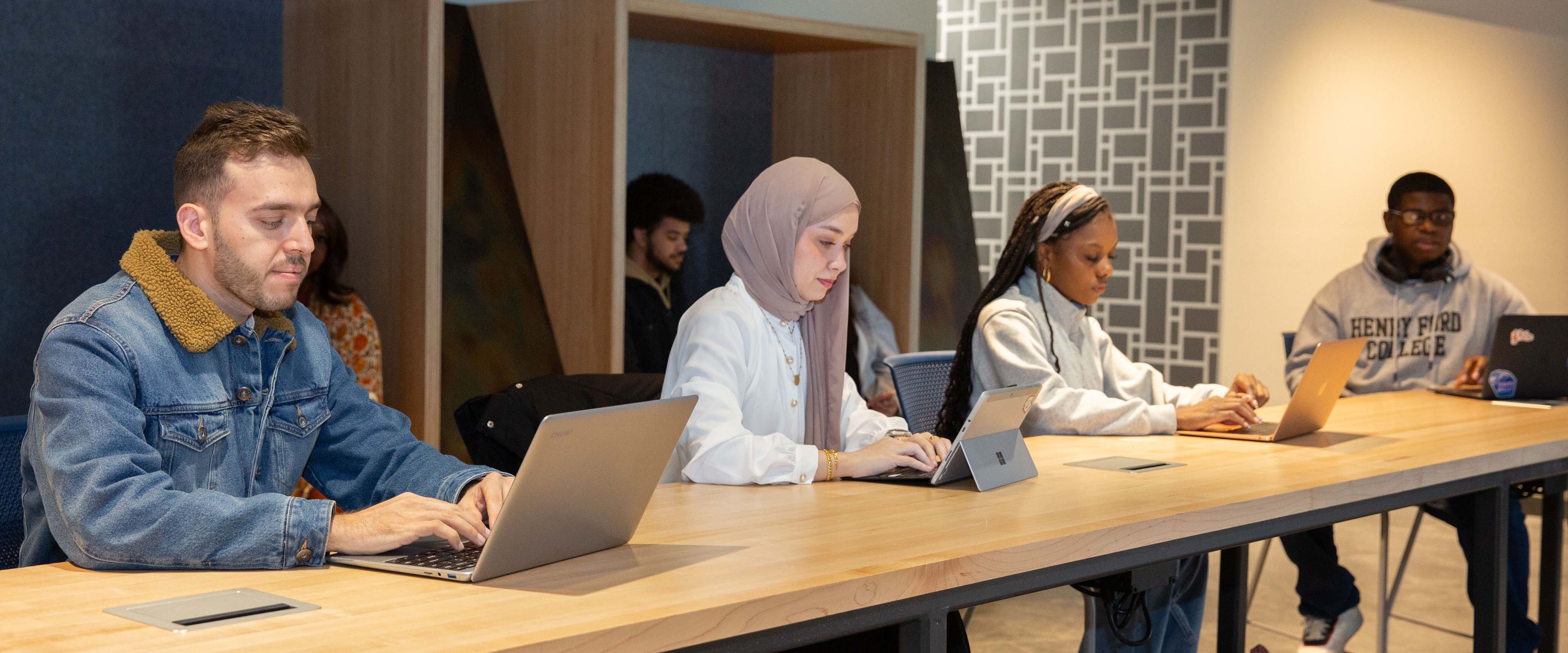 Students working on laptops at a long wooden table