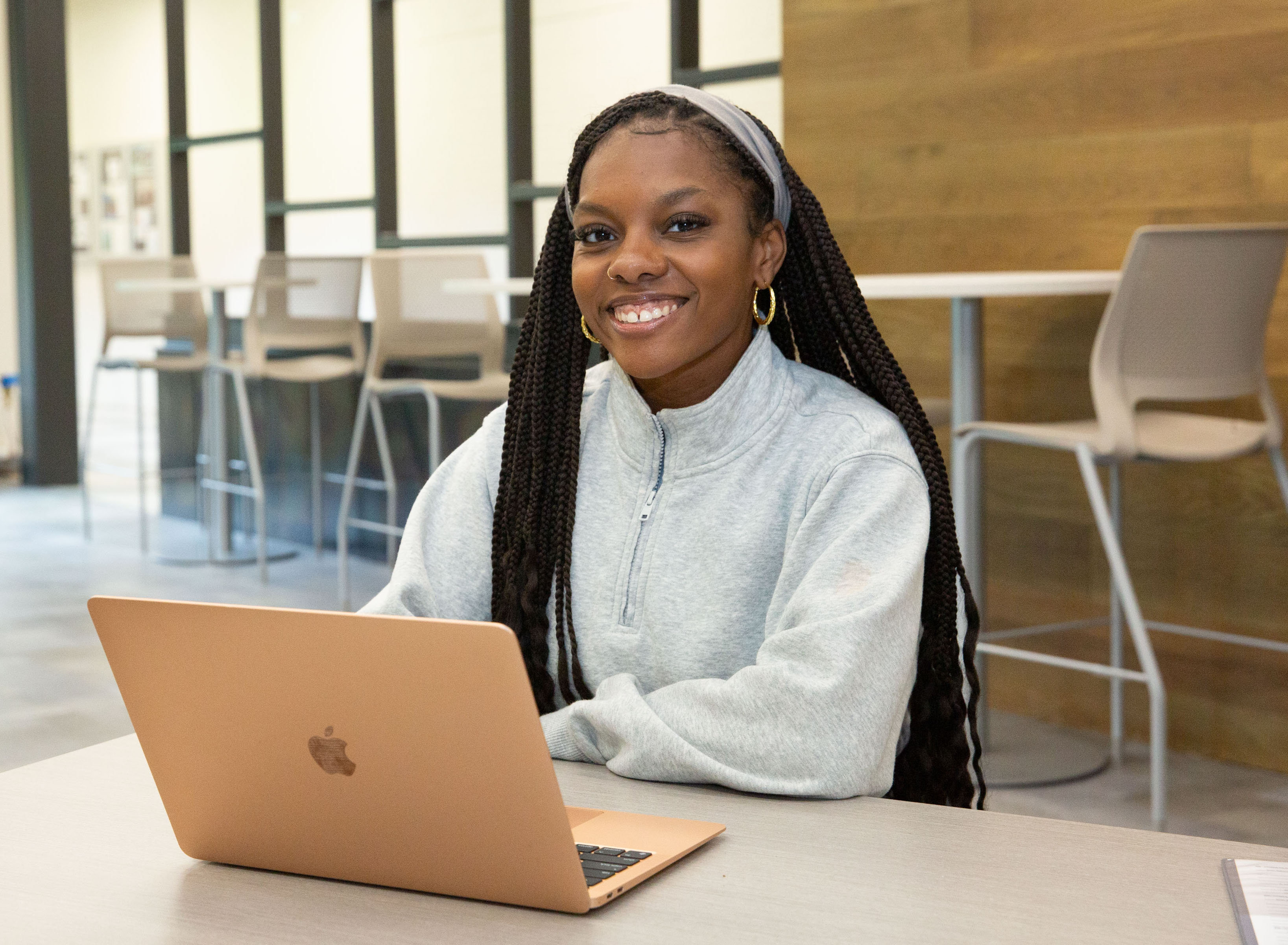 Smiling student sitting at a table with a laptop