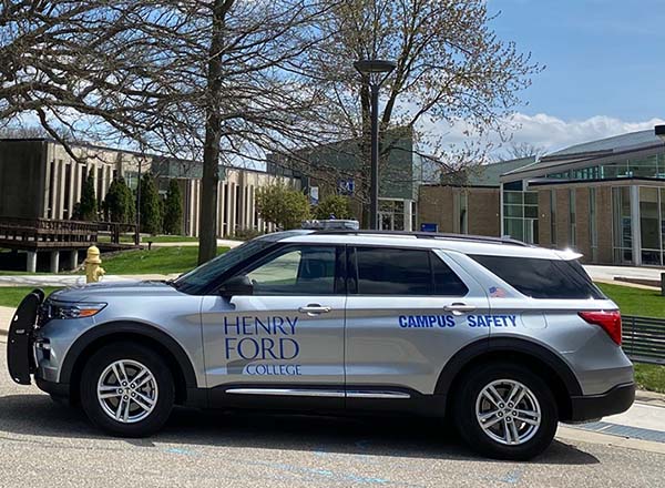 Two silver vehicles with blue Henry Ford College Campus Safety decals on the side.
