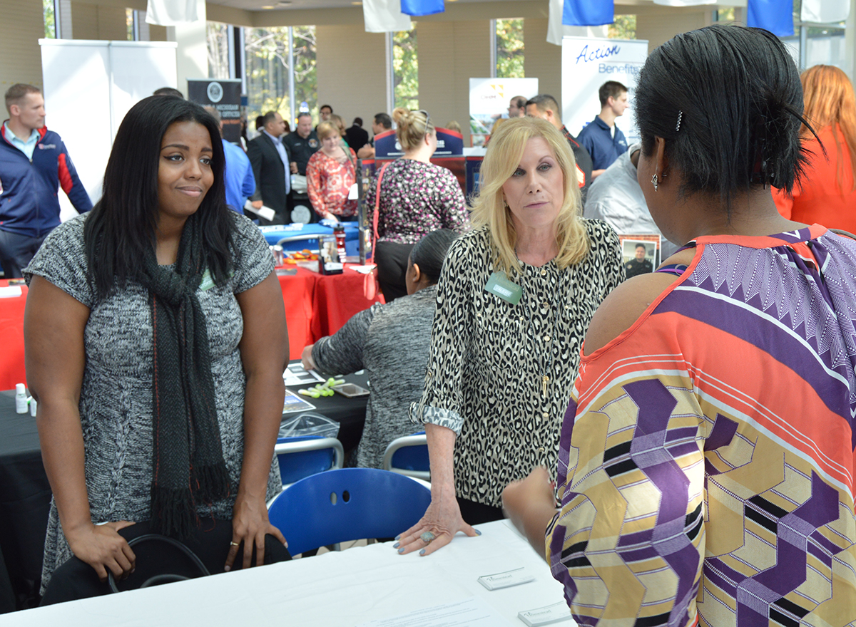 Student speaking to two potential employers at a booth at an HFC career fair