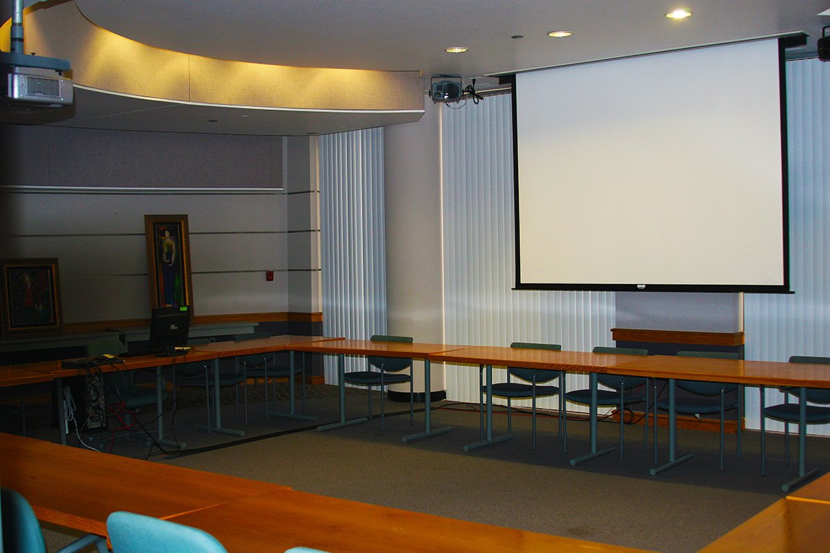 Photograph of Ghafari Conference room showing extended projection screen and chairs arranged around tables