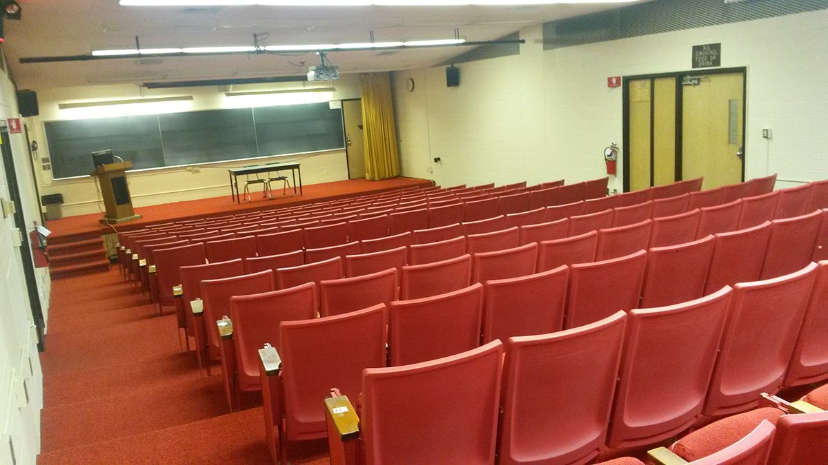 Photograph of the Liberal Arts Auditorium, containing rows of red seats with attached writing surfaces