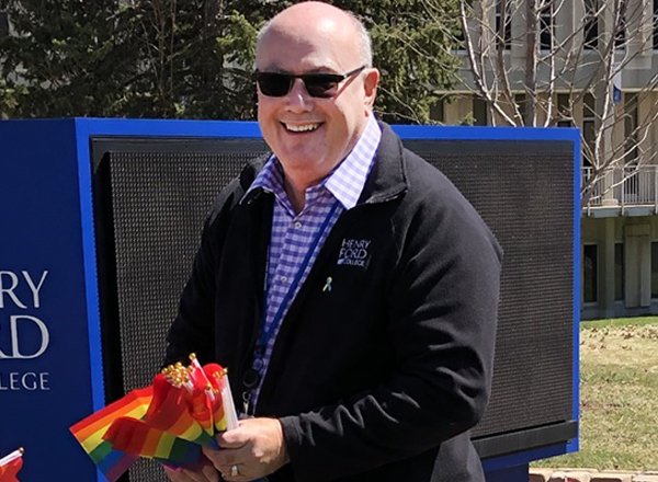 A photo of Troy Gibson holding rainbow flags